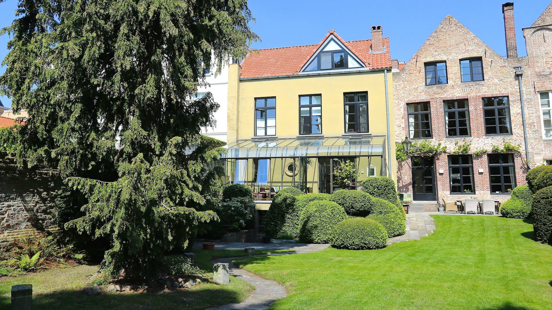 monumentaal HERENHUIS met prachtige tuin uitgevend op de Groenerei – 13e eeuwse kern, 18e eeuwse gevel in rococostijl – toprenovatie met oa 4 slpks, 4 badk en lift.